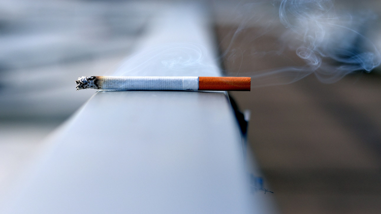 An image of a lit cigarette on the railing: a habit to avoid as part of skincare tricks and tips