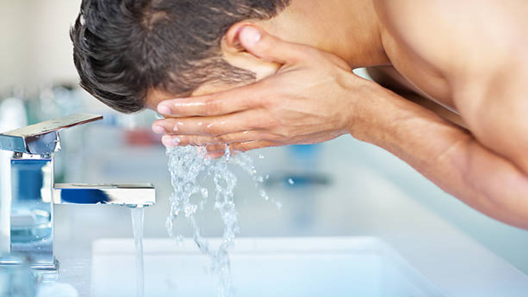 A person washing his face as part of skincare tricks and tips